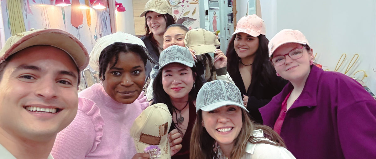 Group of people wearing hairnets taking a selfie in a room with floral decorations.