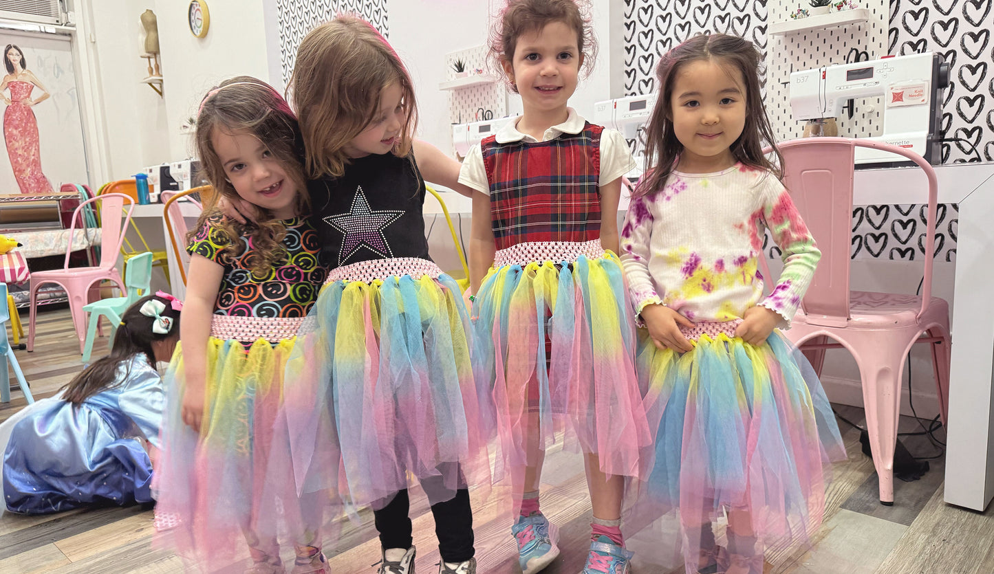 girls wearing tutus standing in front of sewing machines